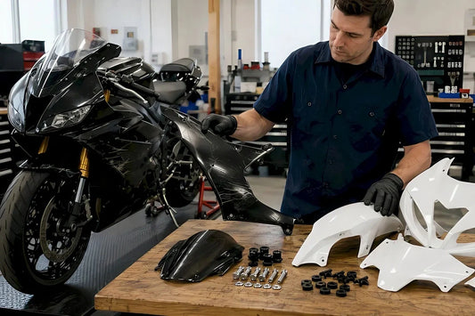 Mechanic comparing damaged motorcycle fairing with replacement fairing panels and hardware in a workshop